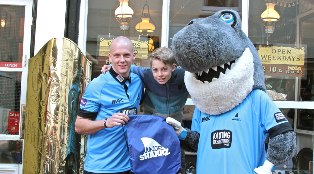 Sussex player Lewis Hatchett with Sid the Shark and a Junior Sharkz member