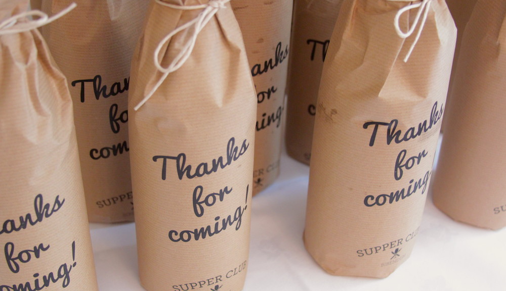 Bottles of wine wrapped in brown paper with 'Thanks for coming!' printed on the outside.